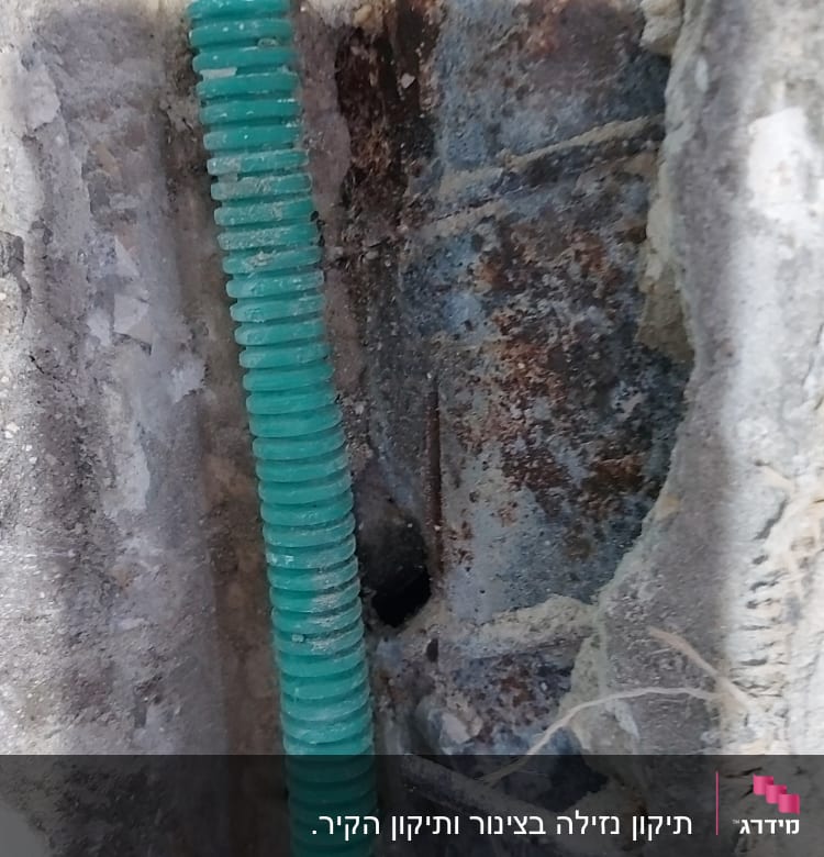 צינור ירוק בקיר עם חלודה וסדקים